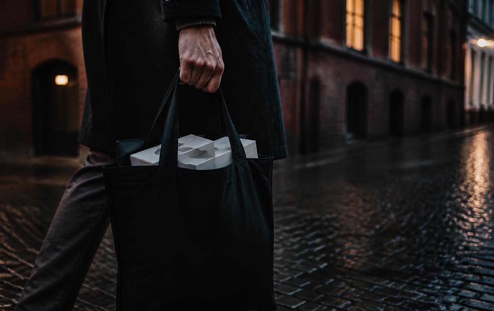 Fotinlägg hämtas hos Idrottsortopedin i Göteborg, buren i en svart kasse på en regnvåt gata i kvällsljus.